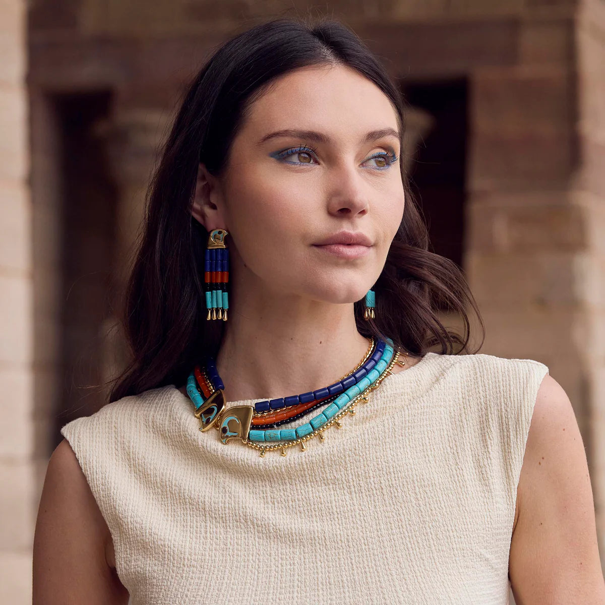 model wearing strand necklace with a cream top 