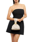 model wearing a black strapless dress holding a bag on her wrist that i cream with a hold detail on a white background 