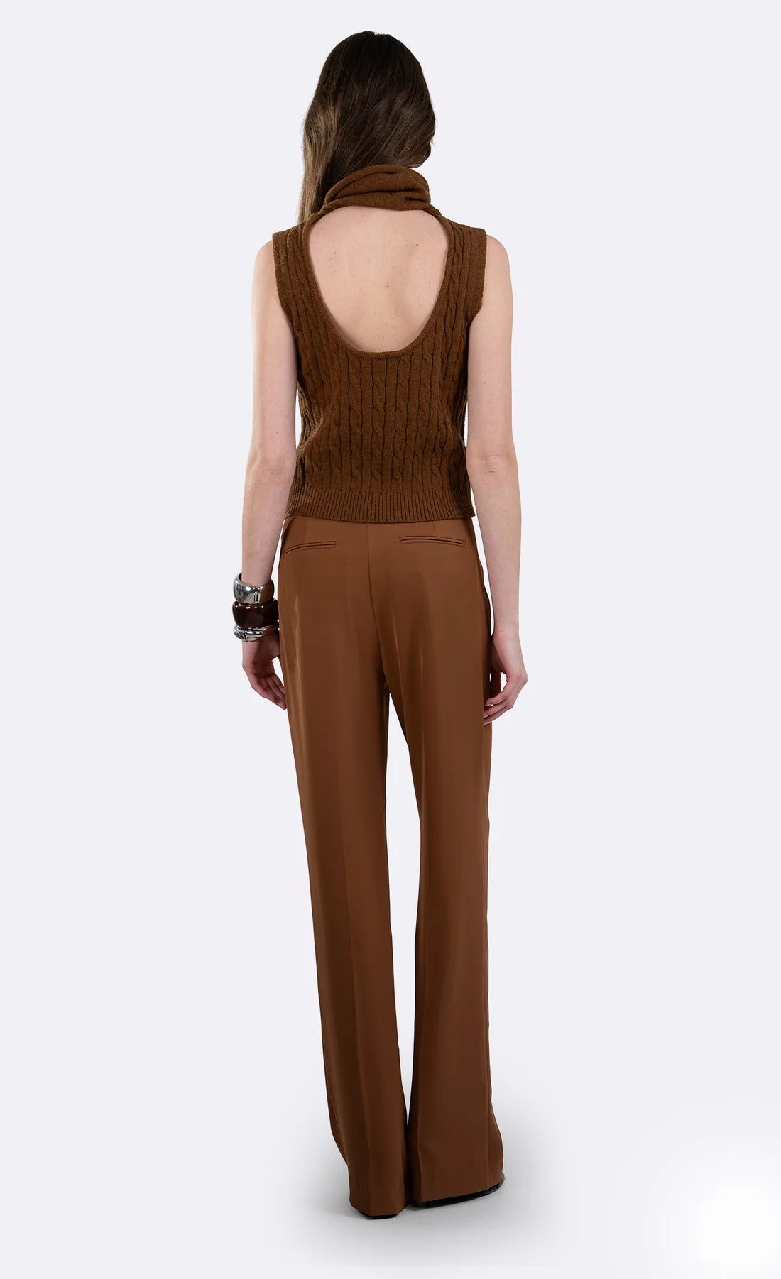 A woman shown from the back wearing a brown sleeveless knit top with an open back and matching wide-leg pants, photographed against a light gray studio background.