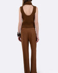 A woman shown from the back wearing a brown sleeveless knit top with an open back and matching wide-leg pants, photographed against a light gray studio background.