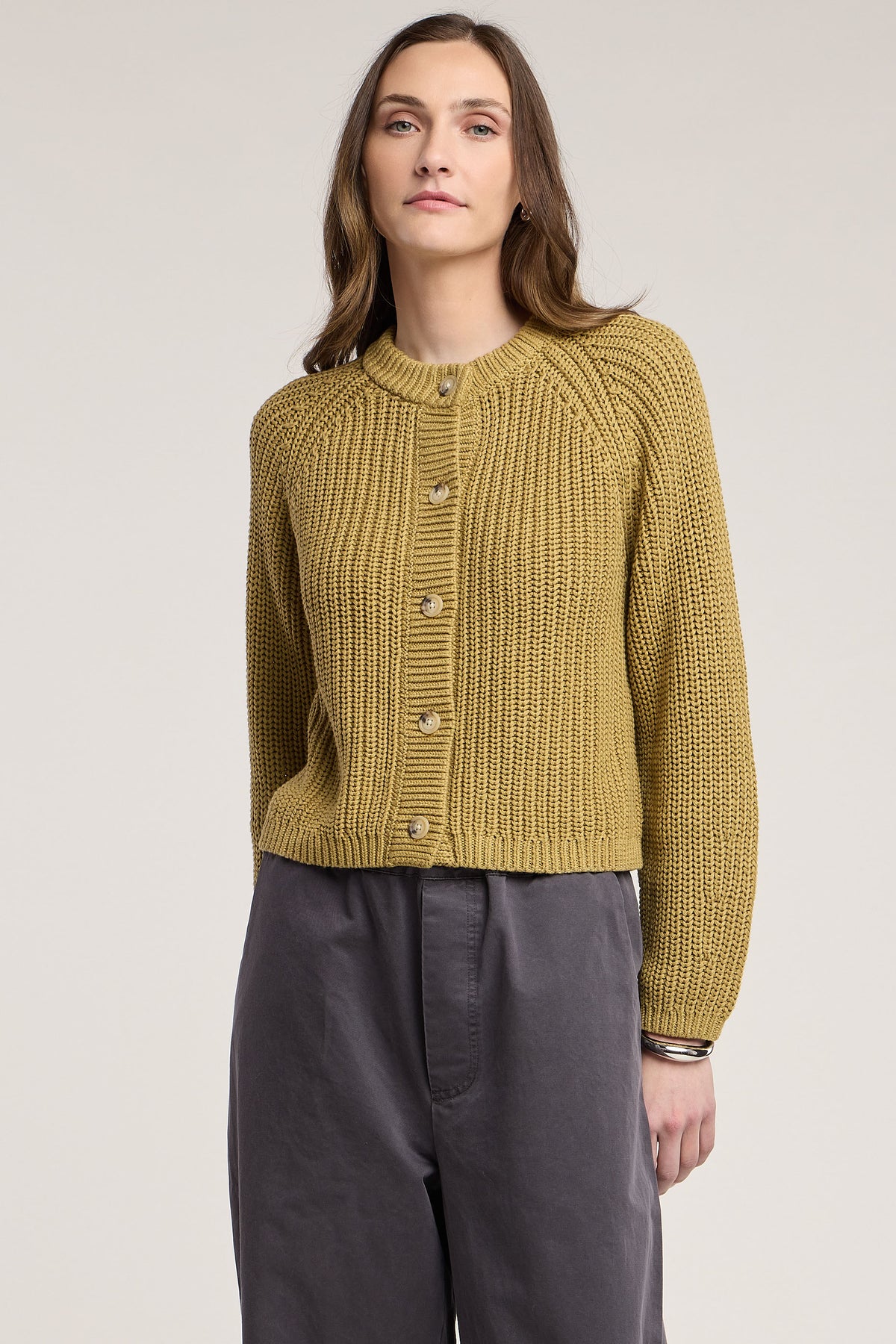 model wearing a khaki chunky cardigan on a cream background