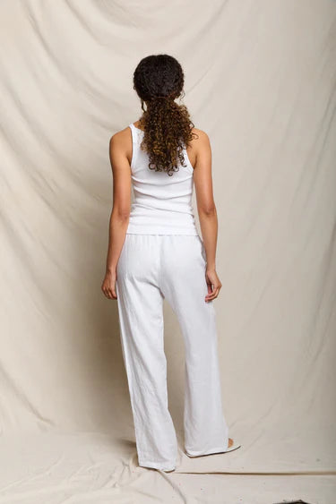 Person wearing a white sleeveless top and pants against a plain background