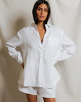 Woman wearing a white shirt and shorts against a plain background