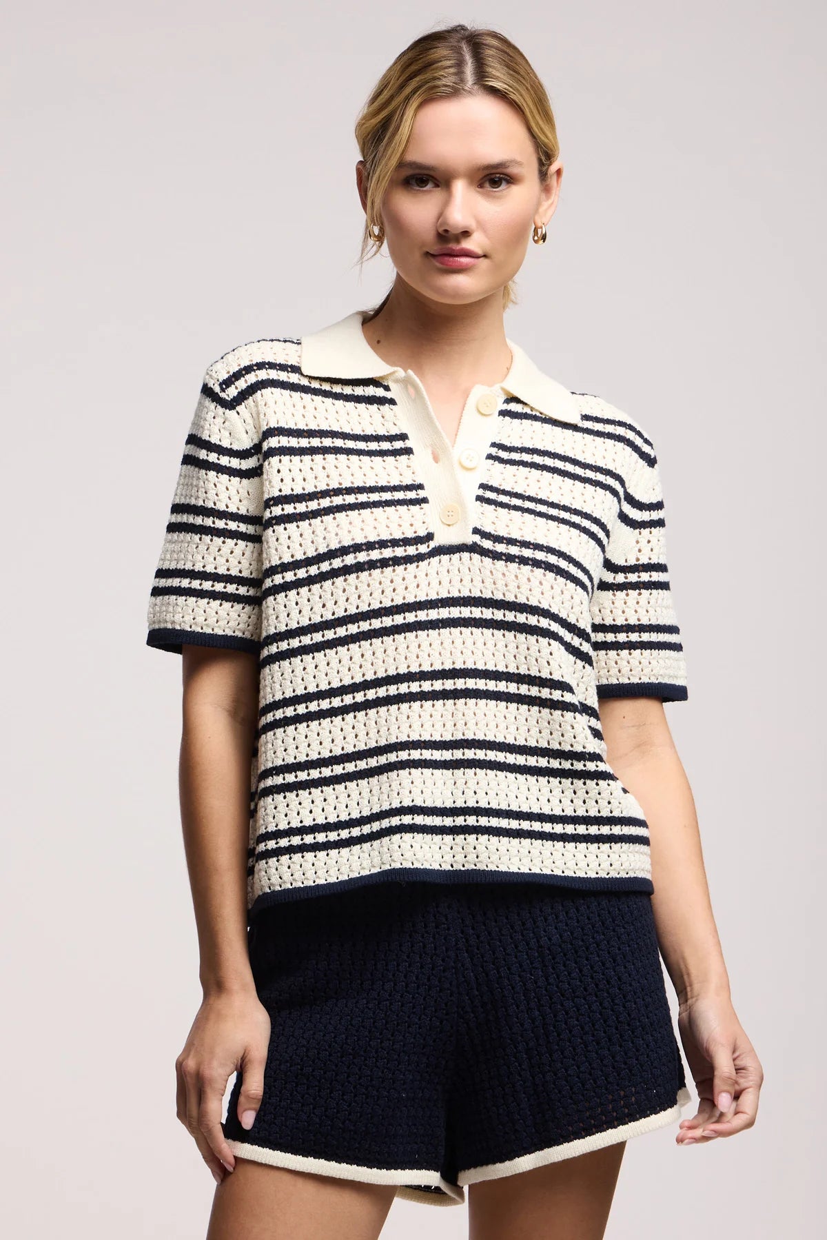 Model wearing the lumae milk and navy stripe short sleeve polo top with shorts on a white background, front