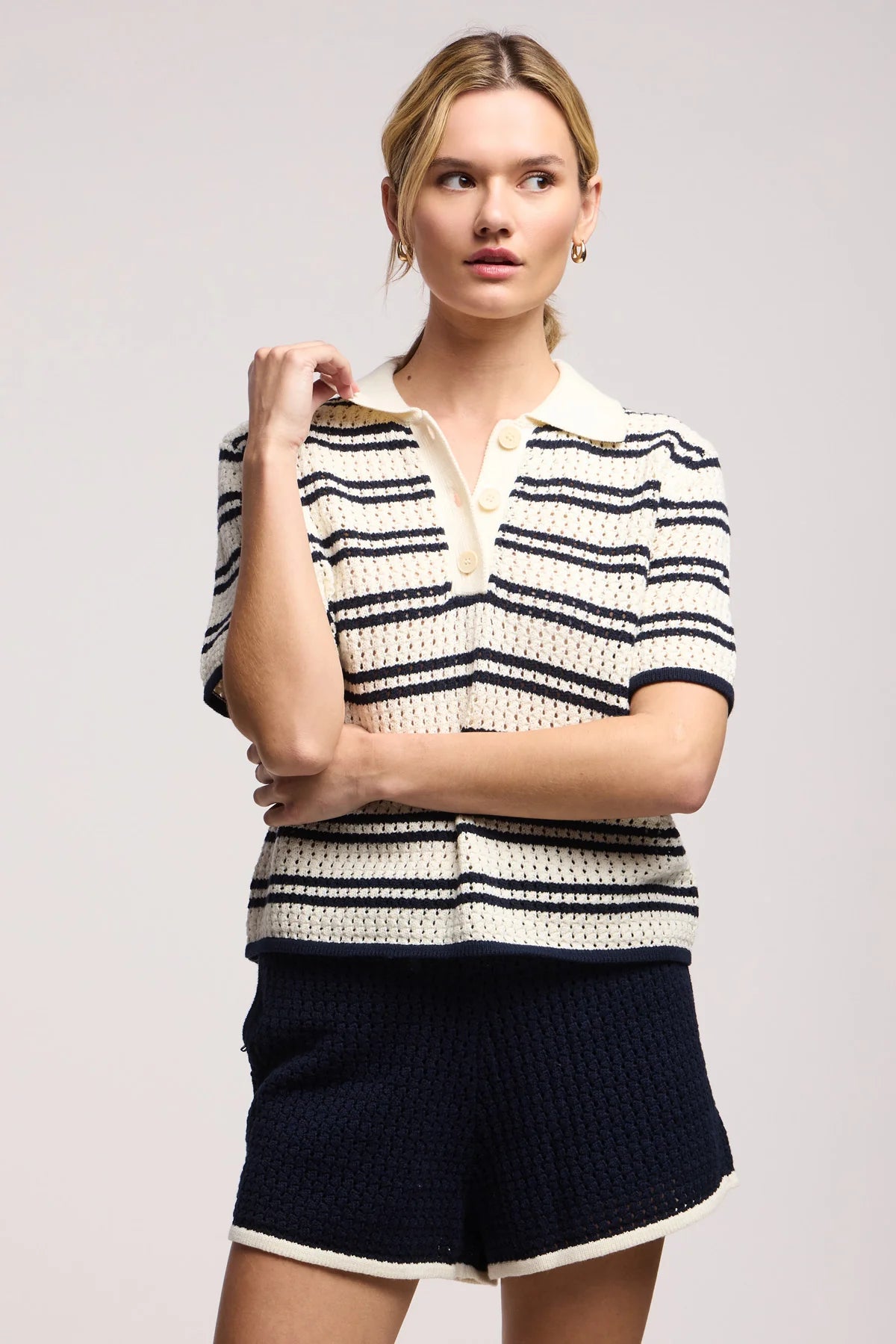 Model wearing the lumae milk and navy stripe short sleeve polo top with shorts on a white background, front
