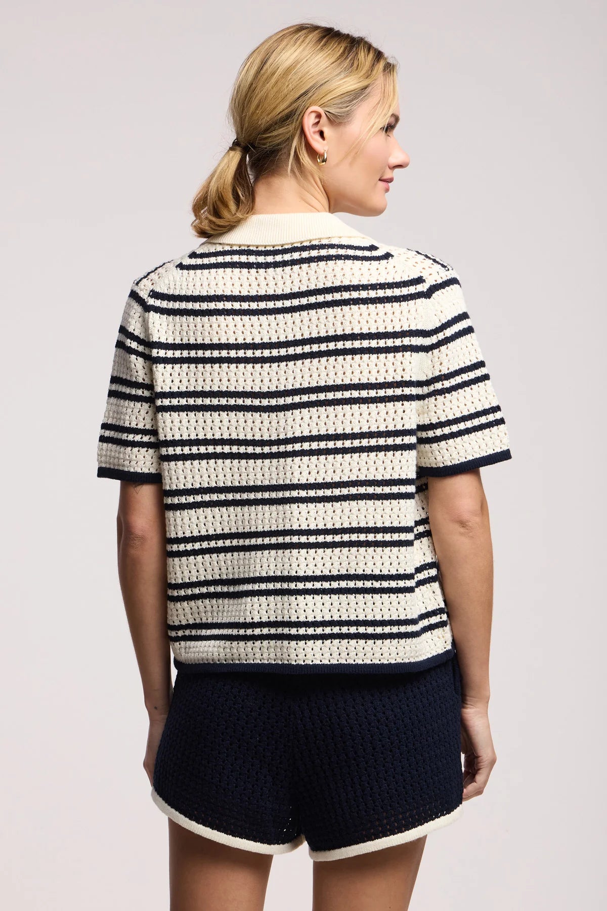 Model wearing the lumae milk and navy stripe short sleeve polo top with shorts on a white background, back