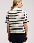Model wearing the lumae milk and navy stripe short sleeve polo top with shorts on a white background, back