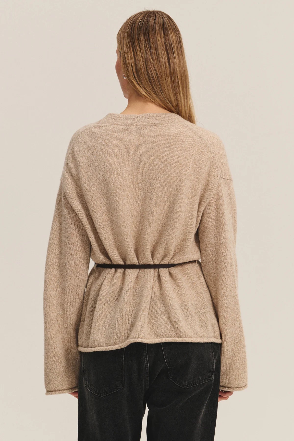 Beige long-sleeve top worn by a person on a beige background