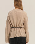 Beige long-sleeve top worn by a person on a beige background