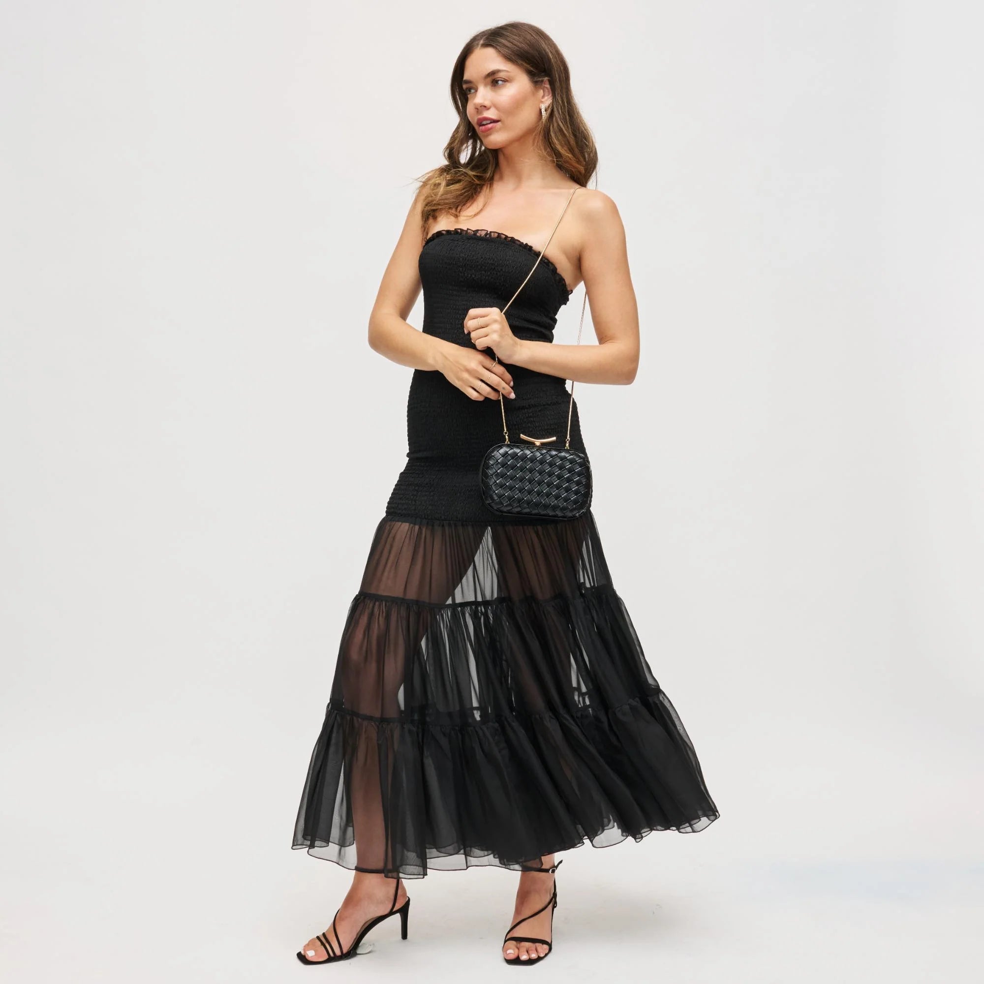 Woman wearing a black dress with sheer panels on a white background