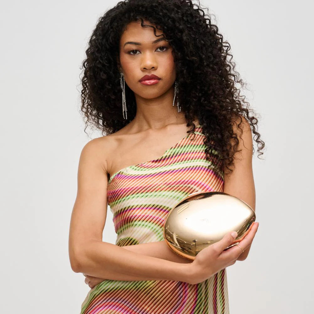 Woman holding a gold clutch against a plain background