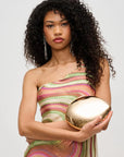 Woman holding a gold clutch against a plain background