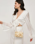 Woman in a white dress holding a beige handbag with floral patterns against a plain background