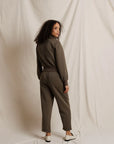 Woman wearing a brown outfit standing against a plain background