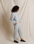 Person wearing a light gray outfit against a plain background, side view
