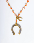 Necklace with a gold horseshoe pendant and orange beads on a white background
