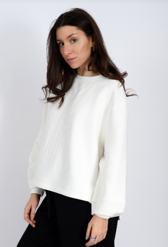 Woman wearing a white sweater against a plain background