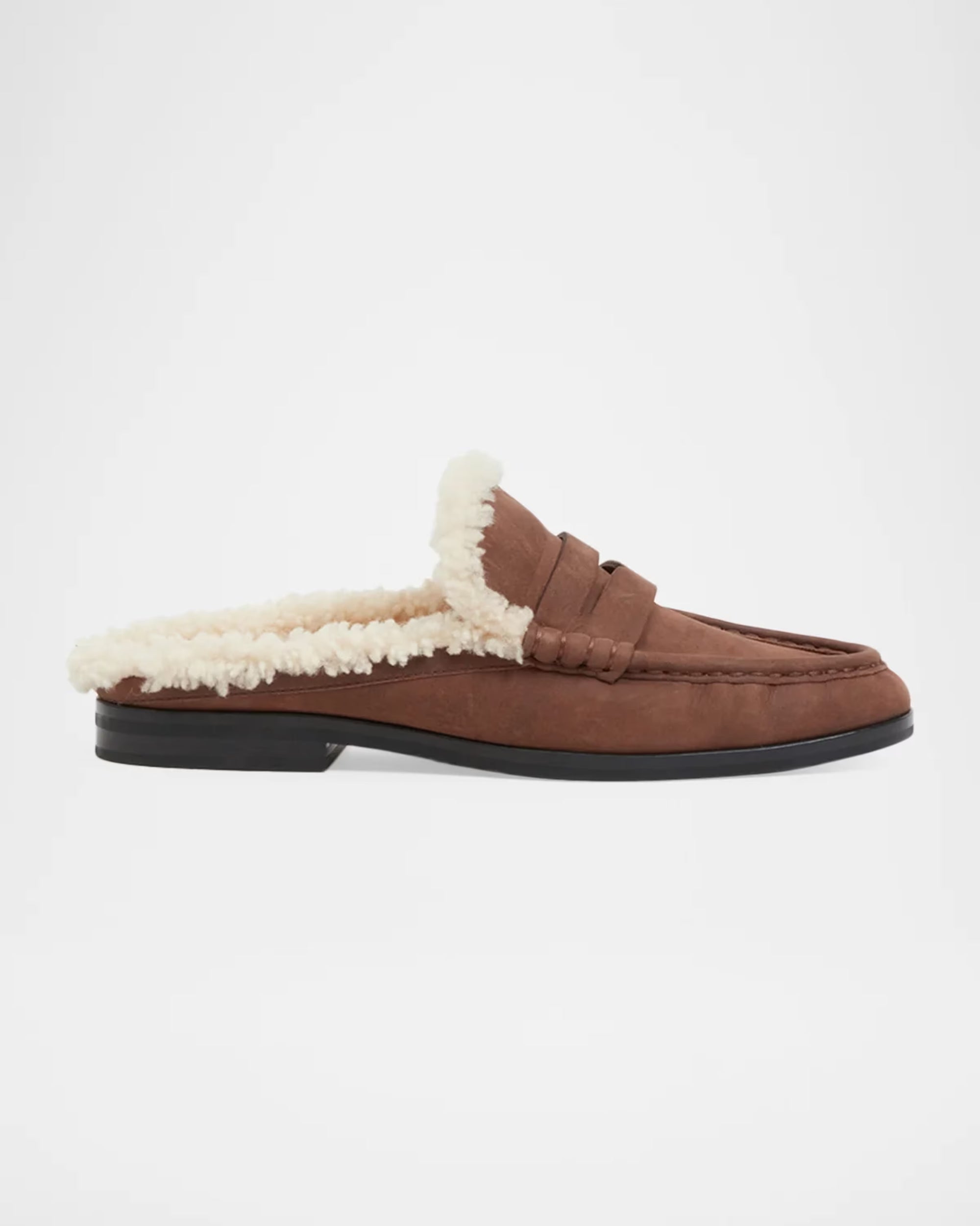 A brown suede slip-on loafer mule with a thick cream sherpa lining and a black sole, shown in profile against a light gray background.