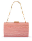 A rectangular wooden clutch bag with horizontal slats in a pink wood grain finish, featuring a gold-tone metal clasp and a gold chain shoulder strap, shown on a plain white background.