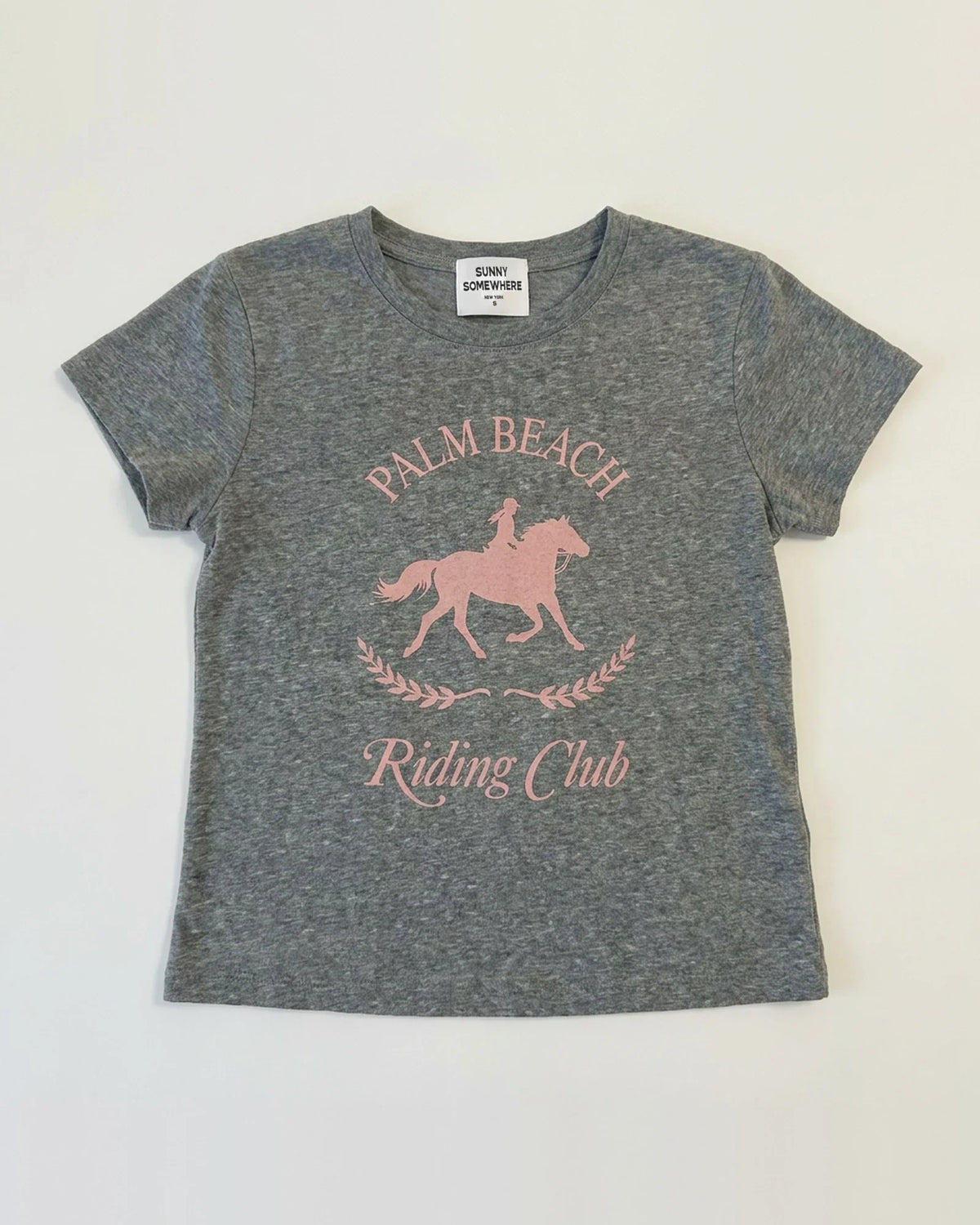 A heather gray short-sleeve t-shirt with a pink graphic print of a horse rider on a horse and the text 'PALM BEACH Riding Club' on the front, laid flat against a white background.