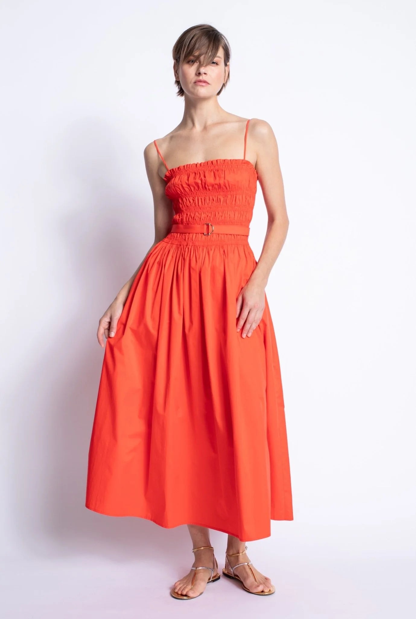Woman wearing a bright orange dress against a white background