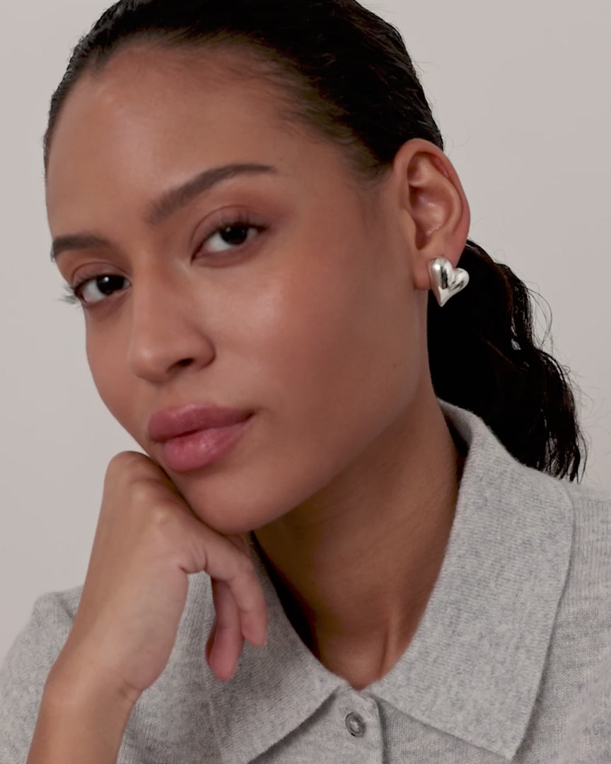 video of model wearing silver heart earrings