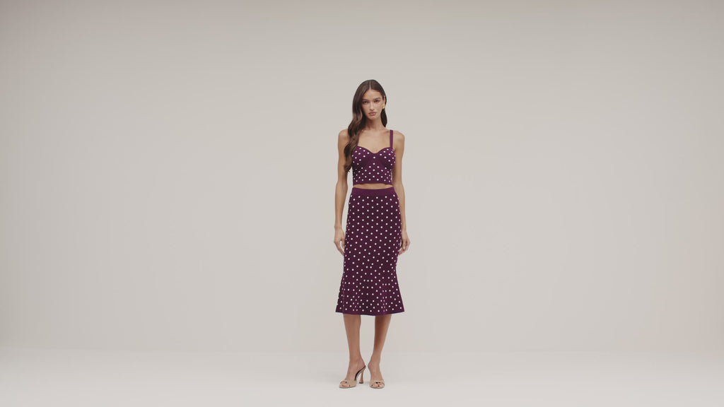 model wearing a dark plum polka dot outfit on a white back ground