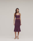 model wearing a dark plum polka dot outfit on a white back ground