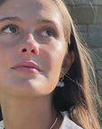 video of a woman wearing gold earrings with pink and aquamarine stones