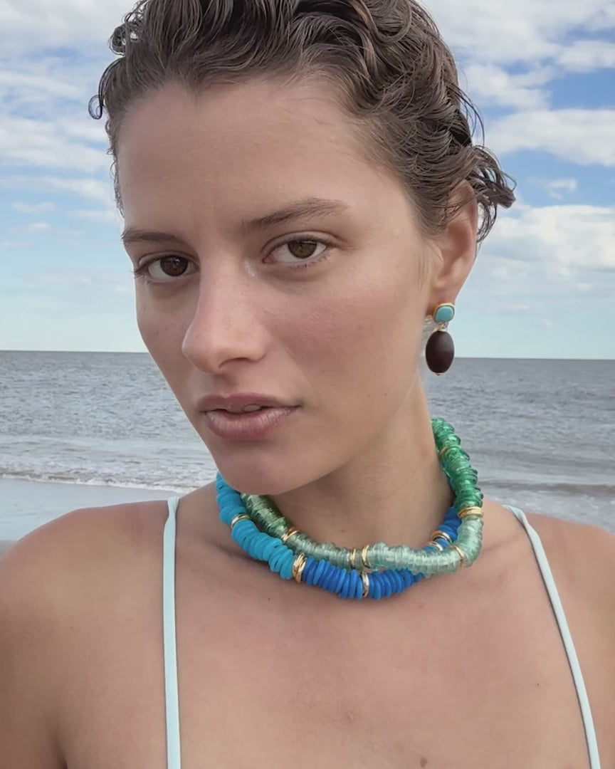 model wearing beaded necklaces on a beach