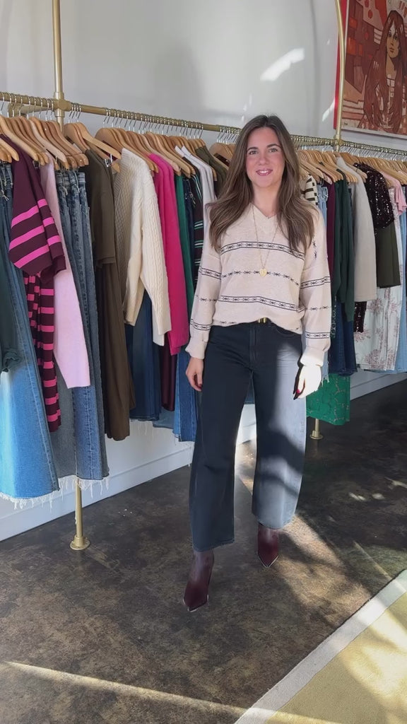 Person in store wearing beige sweater, dark jeans and calf hair booties