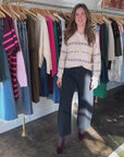 Person in store wearing beige sweater, dark jeans and calf hair booties