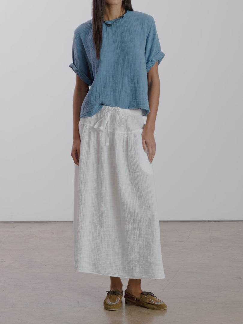 Video of woman in a white skirt and blue top on a white background