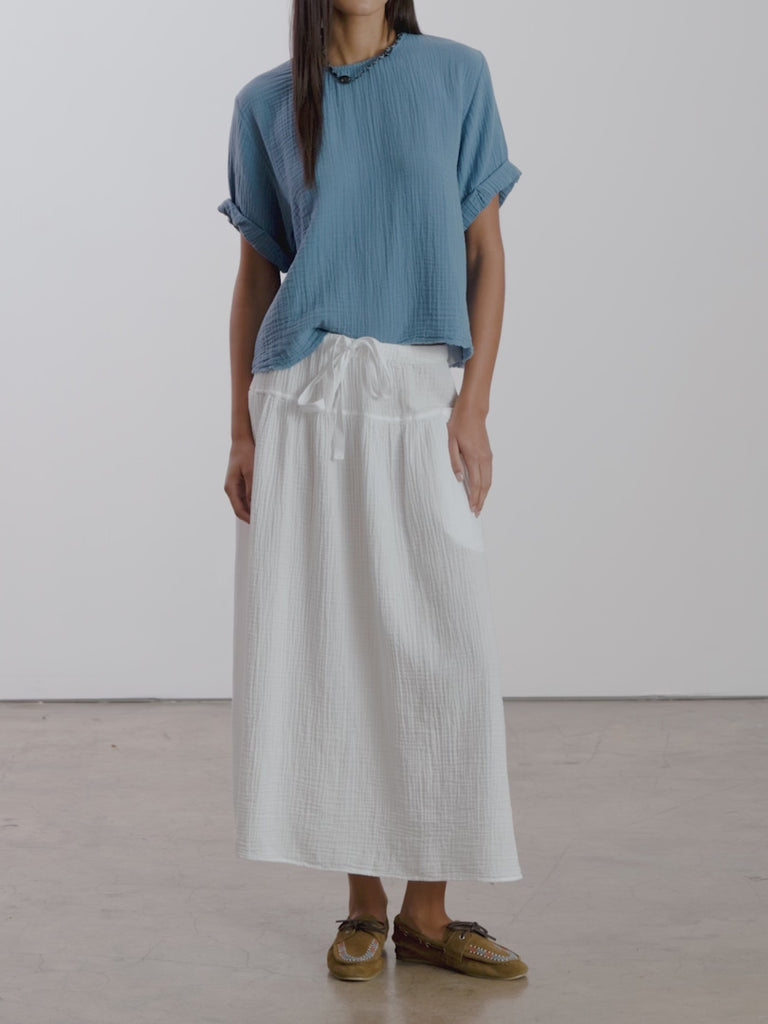 Video of woman in a white skirt and blue top on a white background