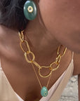Video of woman wearing a stone drop earrings and gold necklaces