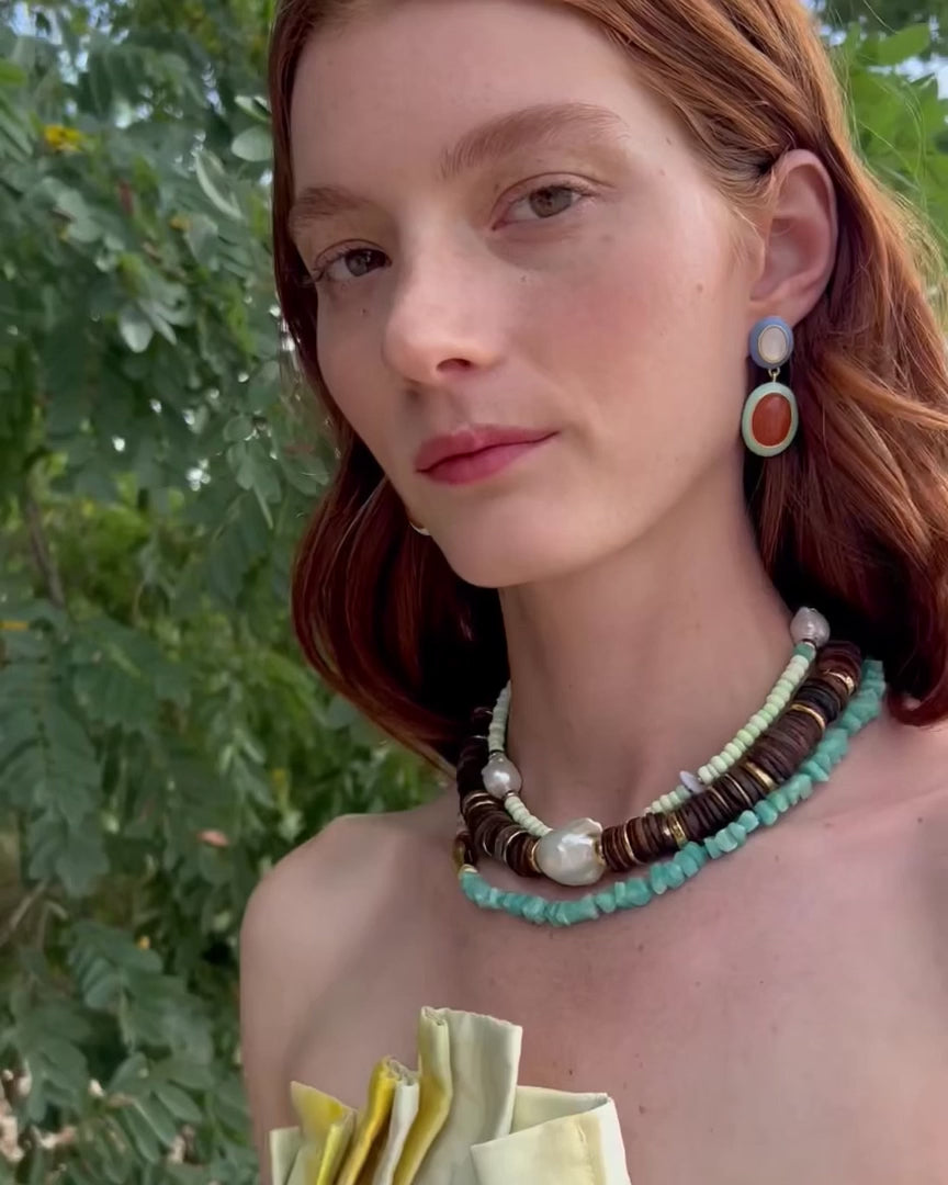 Woman modeling necklace stack and multicolor earrings