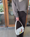 Woman modeling the Winston Sweater, brown jeans and Tommy beaded bag