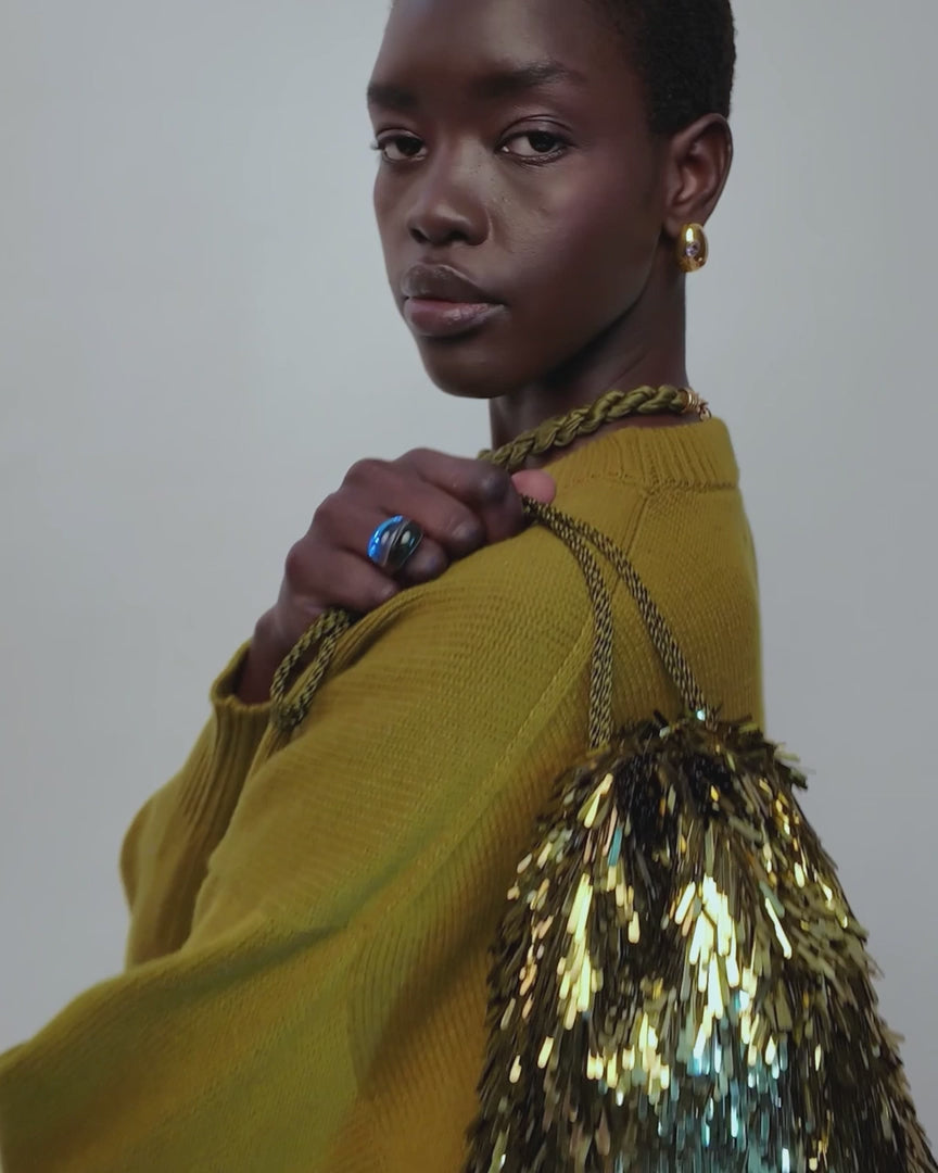 video of a model wearing a blue glass ring and fringe gold bag
