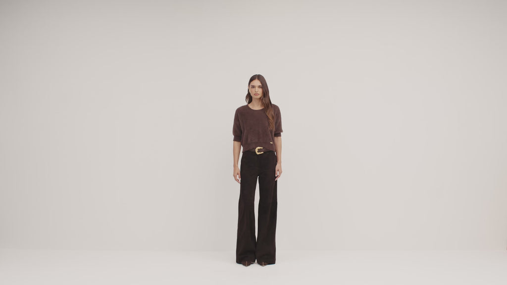 a video of a model wearing a brown fuzzy cropped sweater and dark brown wide-leg pants, set against a plain off-white background.