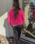 Woman wearing Zeta Ola Sweater with a rhinestone button up, Krewe sunglasses and Ren pants