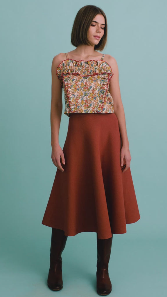 video of a woman modeling a floral cami top and rust colored skirt with boots