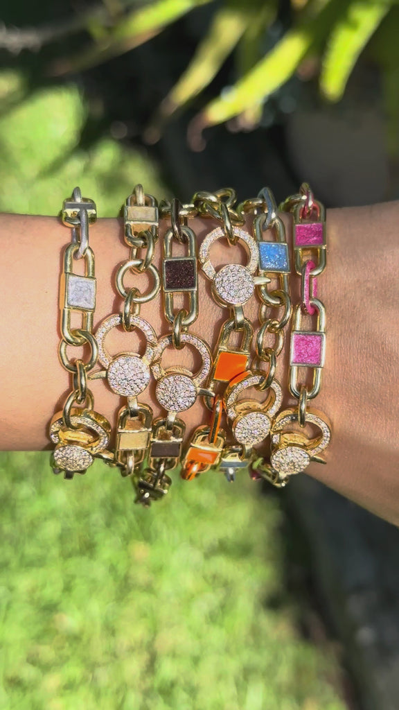 video of gold-tone chain link bracelets with rectangular enamel inlays and a sparkling crystal-encrusted clasp, shown on a plain white background.