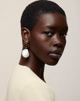 A close-up portrait of a model with short dark hair wearing a cream-colored top and Orbit Earrings in Pearl