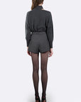 A model shown from the back wearing a dark gray ribbed long-sleeve top and matching gray pinstriped shorts, paired with sheer black tights and black high heels, against a light gray studio background.