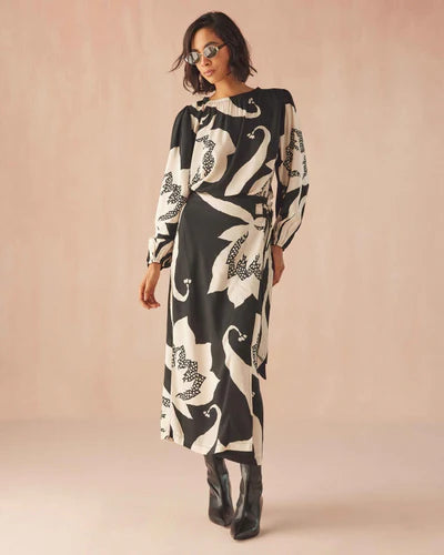 Woman wearing a black and white patterned dress with long sleeves on a beige background