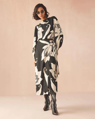 Woman wearing a black and white patterned dress against a beige background