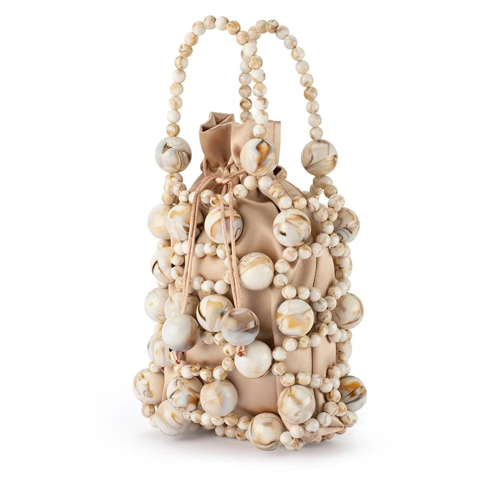Beige handbag with shell embellishments on a white background
