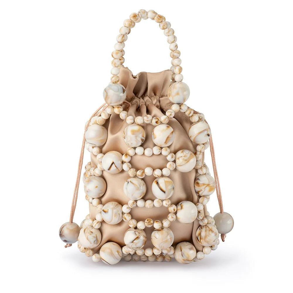 A drawstring pouch bag made of beige satin fabric and decorated with cream and beige marbled beads, featuring a top handle and drawstring ties, shown on a white background.