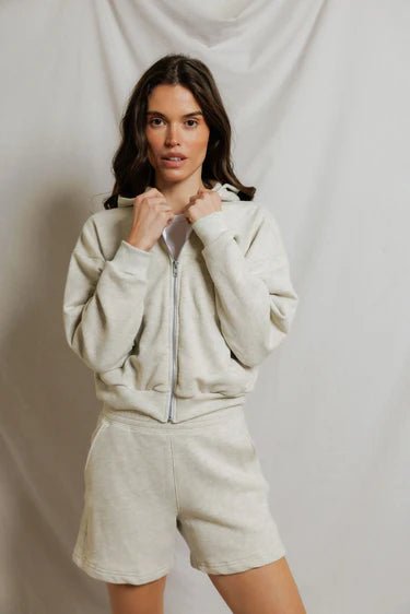 model wearing a zip up hoodie and lounge shorts in the color oatmeal