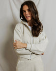model wearing a zip up hoodie and lounge shorts in the color oatmeal